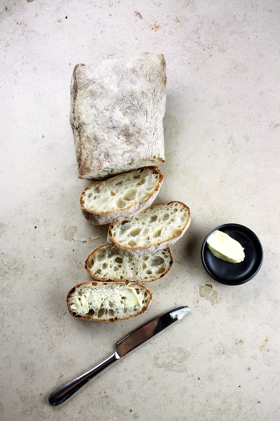 Ciabatta loaf and slices showing an open, irregular crumb